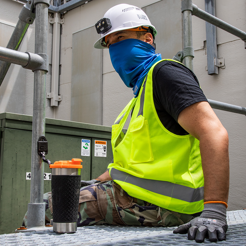 A person wearing a safety vest and a helmet sitting on a metal platform</p>
<p>Description automatically generated